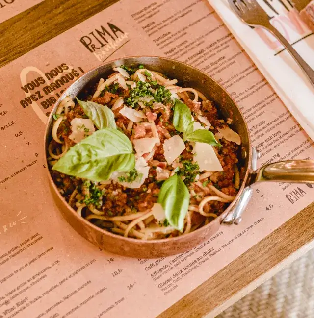Plat de pates dans une cassolette en fonte posee sur une carte du restaurant Prima Bonheur